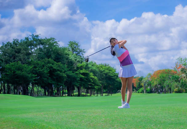 Nainen golf pelaaja toiminnassa on setup osoite takaisin keinu lyödä golfpallon pois T-OFF määränpäähän vihreä, väylä päivällä valo taivas. - Valokuva, kuva