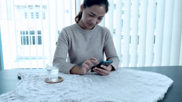 An Asian woman holding a smartphone pretending to be happy. Fulfillment of successful business. - Filmagem, Vídeo