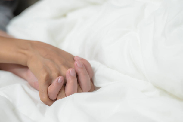 A kéz a férfi és a nő megérinti az ágyon, hogy óvszer biztonságos szex koncepció megelőzése fertőzés és fogamzásgátlók szabályozzák a születési arány vagy biztonságos profilaktikus. Az AIDS világnapja - Fotó, kép