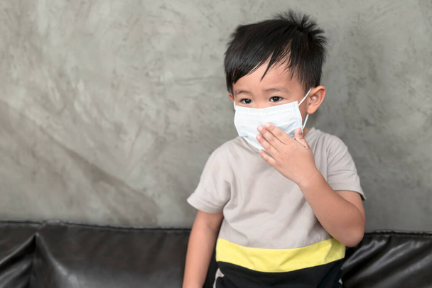 A boy wearing medical face mask for pollution or coronavirus,child itchy eyes and nose, Kid scratching nose while wearing protection mask.Protection against contagious disease, coronavirus. - Photo, Image