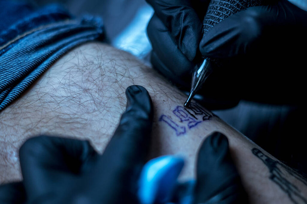 női művész tetováló betűk egy ügyfél lábát - Fotó, kép