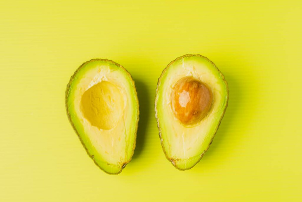 An avocado cut into half with green background - Foto, afbeelding