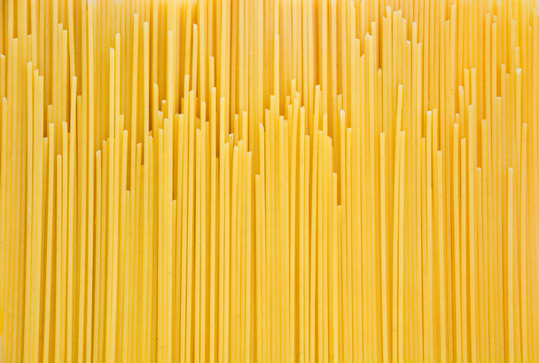 pile of yellow raw spaghetti, yellow pasta background ready for cooking, top view - Photo, Image