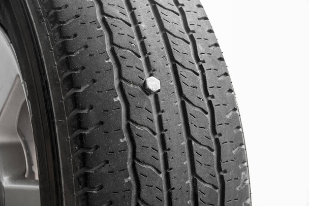 close up de vazamento de pneus de borracha, pneu de automóvel perfurado com uma unha de parafuso de metal, isolado em fundo branco, espaço de cópia - Foto, Imagem