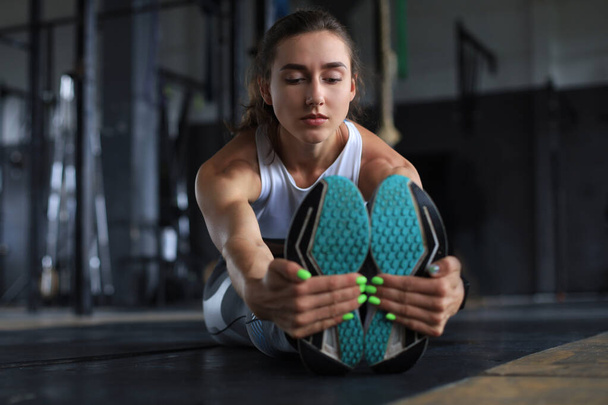 Young sporty woman stretching at the gym - 写真・画像