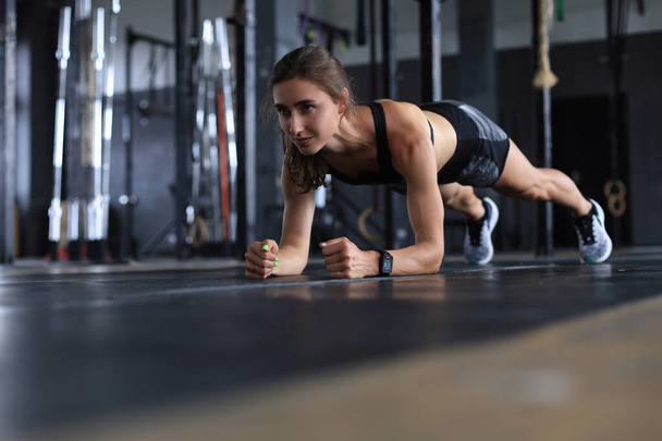 Portrait of a muscular woman on a plank position - Photo, image