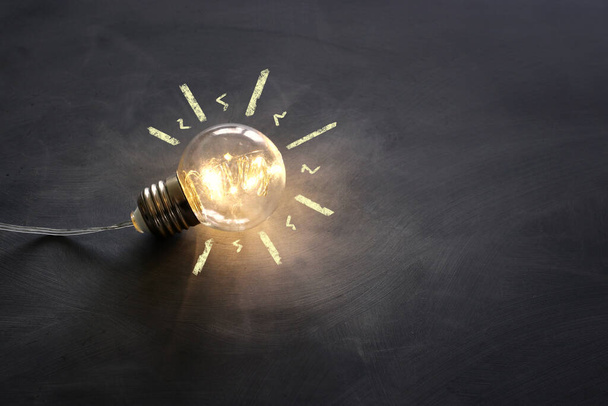 Education concept image. Creative idea and innovation. Light bulb as metaphor over blackboard - Foto, Imagen