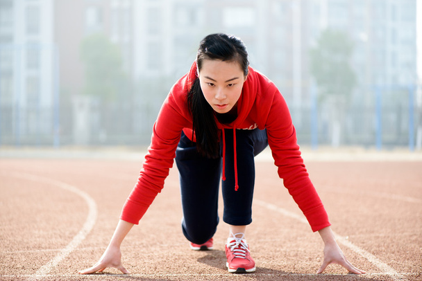 Athletic Chinese woman in start position on track - Photo, Image
