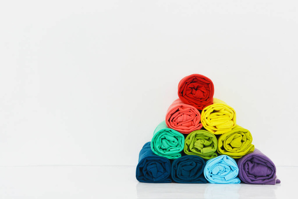 stack of colorful t-shirt rolled up on white background, copy space - Fotó, kép