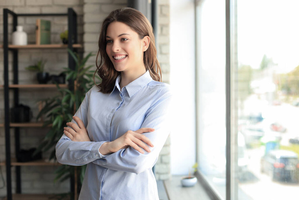 Houkutteleva liiketoiminnan nainen hymyilee seistessään toimistossa - Valokuva, kuva