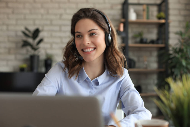Freelance operator talking with headsets and consulting clients from home office - Fotó, kép