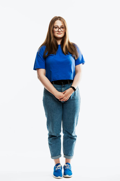 A young girl in jeans and a blue T-shirt is standing. Full height. Isolated on a white background. Vertical. - Фото, изображение