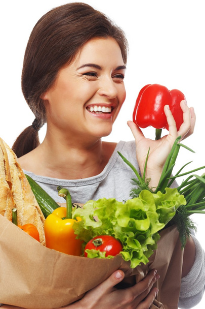 Mulher morena sorridente com saco de supermercado cheio de legumes frescos e páprica vermelha
 - Foto, Imagem
