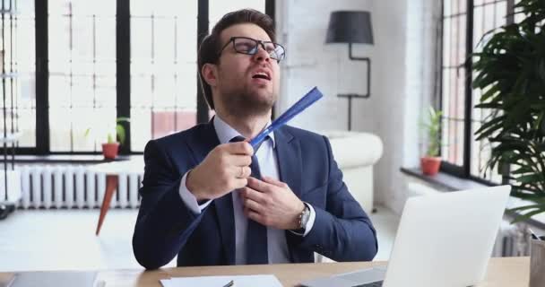 Unhappy tired young sweaty overheated executive manager using paper fan. - Video