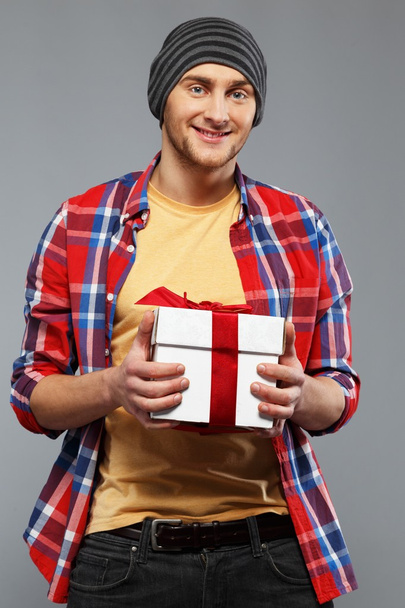 Stylish young man in shirt and beanie hat with gift box - Photo, Image