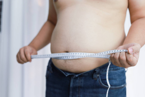 Uomo con pancia grassa nel concetto di dieta. Uomo in sovrappeso toccare la pancia grassa e vuole perdere peso - Foto, immagini