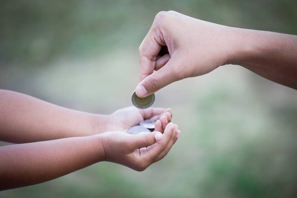 Matka dává mince pro dítě jako úspora peněz koncept v retro barevném tónu - Fotografie, Obrázek