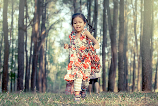 Cute asian little girl running in the park in vintage color tone - Zdjęcie, obraz
