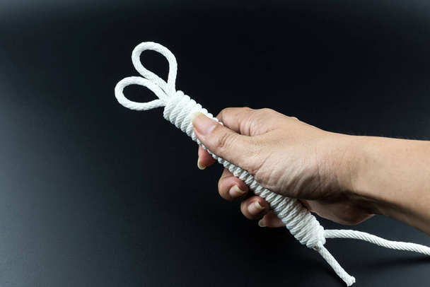 White rope in hand on black background, selective focus. - Photo, Image
