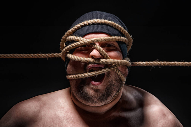 Foto de homem gordo amarrado com corda no rosto
 - Foto, Imagem