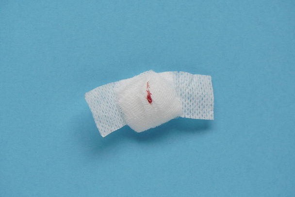 Exames de sangue, pequeno traço de sangue em bandagem com band-aid em fundo azul.Teste de coroonavírus. colheita de sangue
 - Foto, Imagem