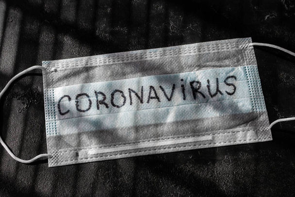 medical mask with the inscription coronavirus closeup on a black background - Foto, Imagen