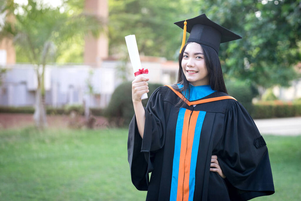 Portrét šťastné a vzrušené mladé asijské absolventky vysoké školy nosí maturitní šaty a klobouk slaví s titulem v univerzitním kampusu na začátku dne. Koncept vzdělávání. - Fotografie, Obrázek