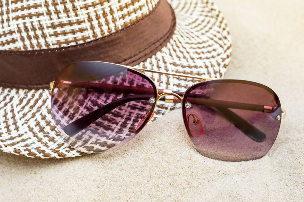 Kumda güneş gözlüğü olan bir yaz şapkası. Kapat.. - Fotoğraf, Görsel