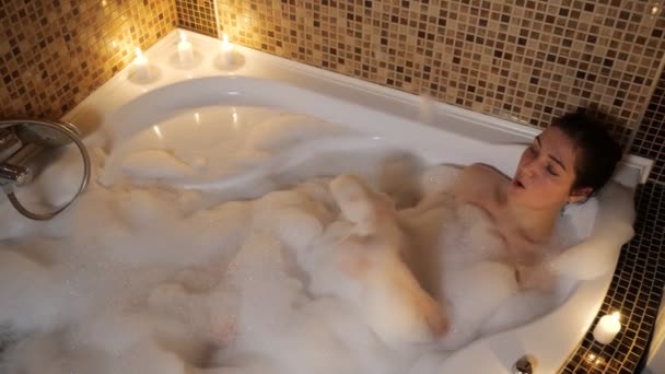 nő fekszik egy buborék fürdő gyertyafénynél és énekel. - Felvétel, videó