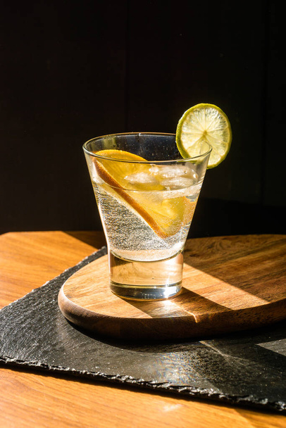 Kylmä kesä herkullinen cocktail limellä ja jäällä lasissa, jossa pisarat mustalla kivipohjalla. - Valokuva, kuva