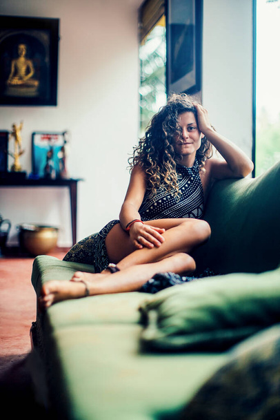 Beautiful curly woman rests on the sofa at the terrace - Photo, Image