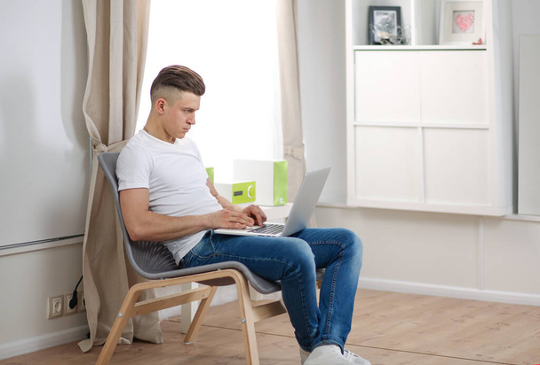 Handsome young man sitting and working on laptop computer - 写真・画像