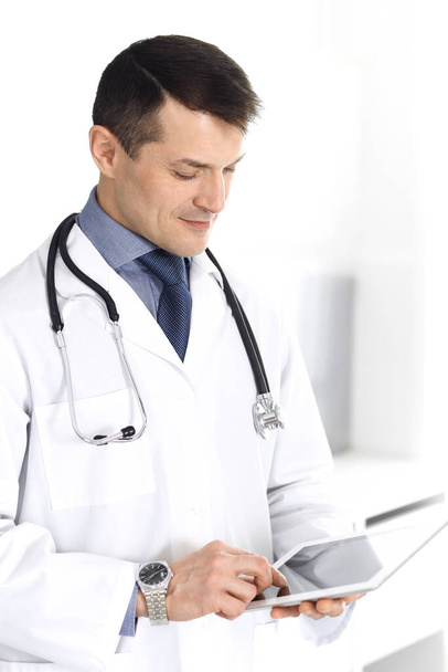 Doctor man using tablet computer for network research or virtual disease treatment. Perfect medical service in clinic. Happy future for modern medicine, medic data and healthcare concepts - Фото, зображення