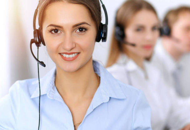 Call center. Focus on beautiful business woman using headset in sunny office - Foto, Imagem