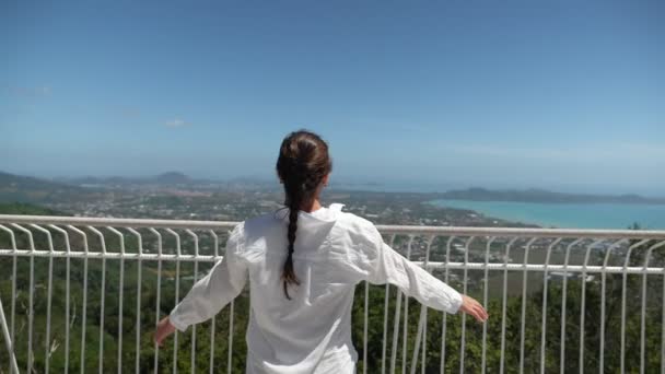 mujer joven en blusa blanca levanta las manos admirando el paisaje
 - Metraje, vídeo