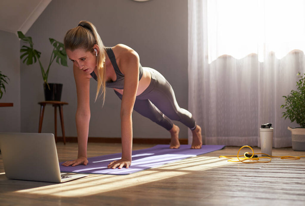 Fiatal nő vesz részt az online fitness osztály előtt laptop. - Fotó, kép