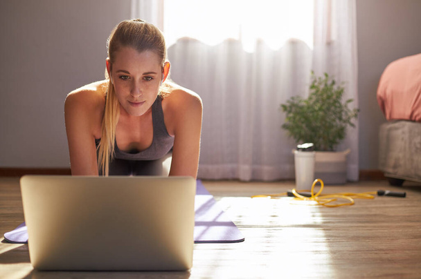 Nuori nainen osallistuu online fitness-luokkaan kannettavan tietokoneen edessä. - Valokuva, kuva