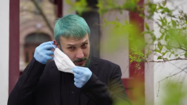 Man in black with dyed hair puts on a mask - Záběry, video