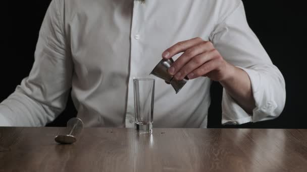 Μπάρμαν ρίχνει μπλε λικέρ Κουρασάο σε ποτήρι από jigger - Πλάνα, βίντεο