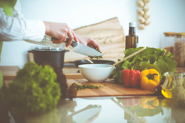 Manos humanas desconocidas cocinando en la cocina. Mujer cortando cebolla verde. Comida saludable y concepto de comida vegetariana
 - Foto, imagen