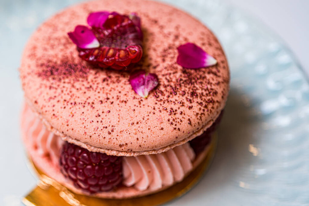 Piękne różowe ciasteczka malinowe Macaron na niebieskim talerzu. Zdrowe jedzenie. Niebieski stół w tle. Widok z góry.  - Zdjęcie, obraz