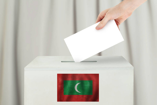 Maldives Concept de vote. L'électeur tient à la main son bulletin de vote pour le vote électoral au bureau de scrutin - Photo, image