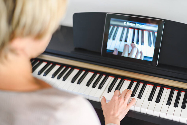 Valkoihoinen nainen opettelee soittamaan pianoa videotunneilla. Virtuaalisen oppimisen käsite - Valokuva, kuva