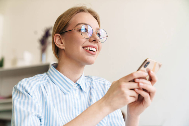 Foto glücklich schöne Architektin in Brille mit Handy beim Entwurf Entwurf am Arbeitsplatz - Foto, Bild