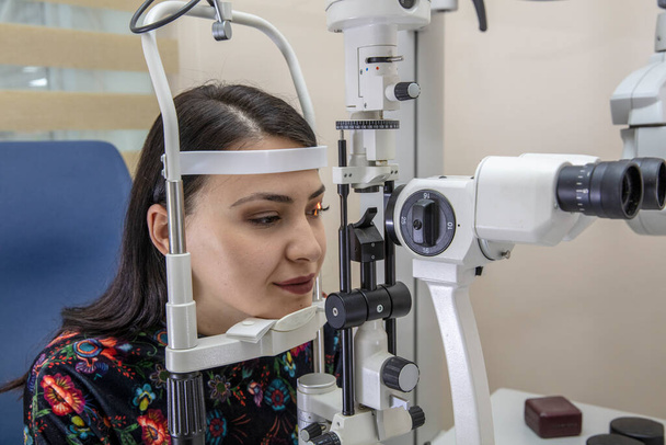 High technology concept health for eye care - okulista okulista lekarz okulista w klinice okulistycznej za pomocą lornetki lampy szczelinowej do młodej kobiety do kontroli wzroku.  - Zdjęcie, obraz