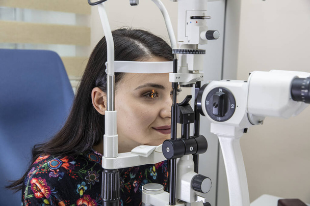 目のケアのためのハイテク概念の健康-目のコントロールのための若い女性に両眼スリットランプを使用して目のクリニックの眼科医の眼科医.  - 写真・画像
