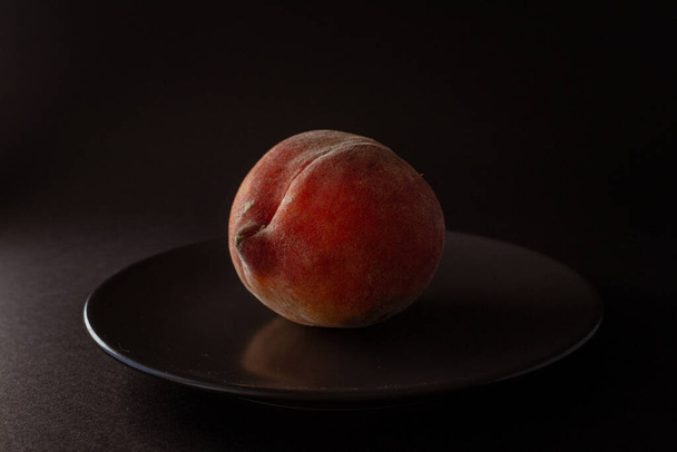 Fresh seasonal peach on black plate on black background - Photo, Image