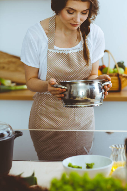 Young brunette woman cooking soup in kitchen. Food and health concept - Fotoğraf, Görsel