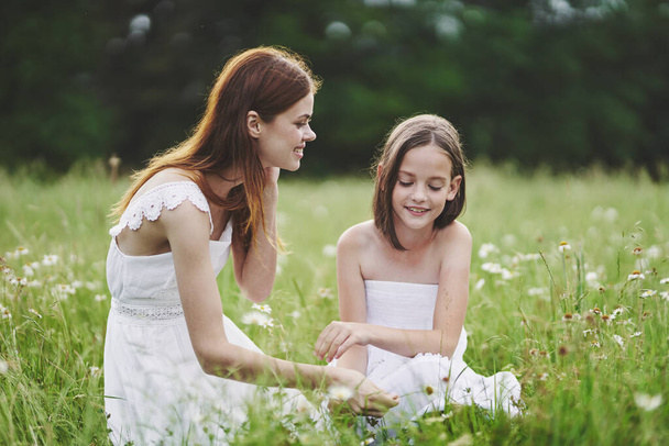 Young mother and her daughter having fun on camomile field - Photo, image
