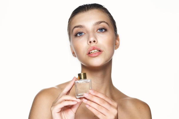 Portret van jonge mooie vrouw met parfumflesje. Studioshoot.   - Foto, afbeelding